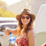 Young female explorer portrait in parking lot about to take a last sip of water before a day of adventure.